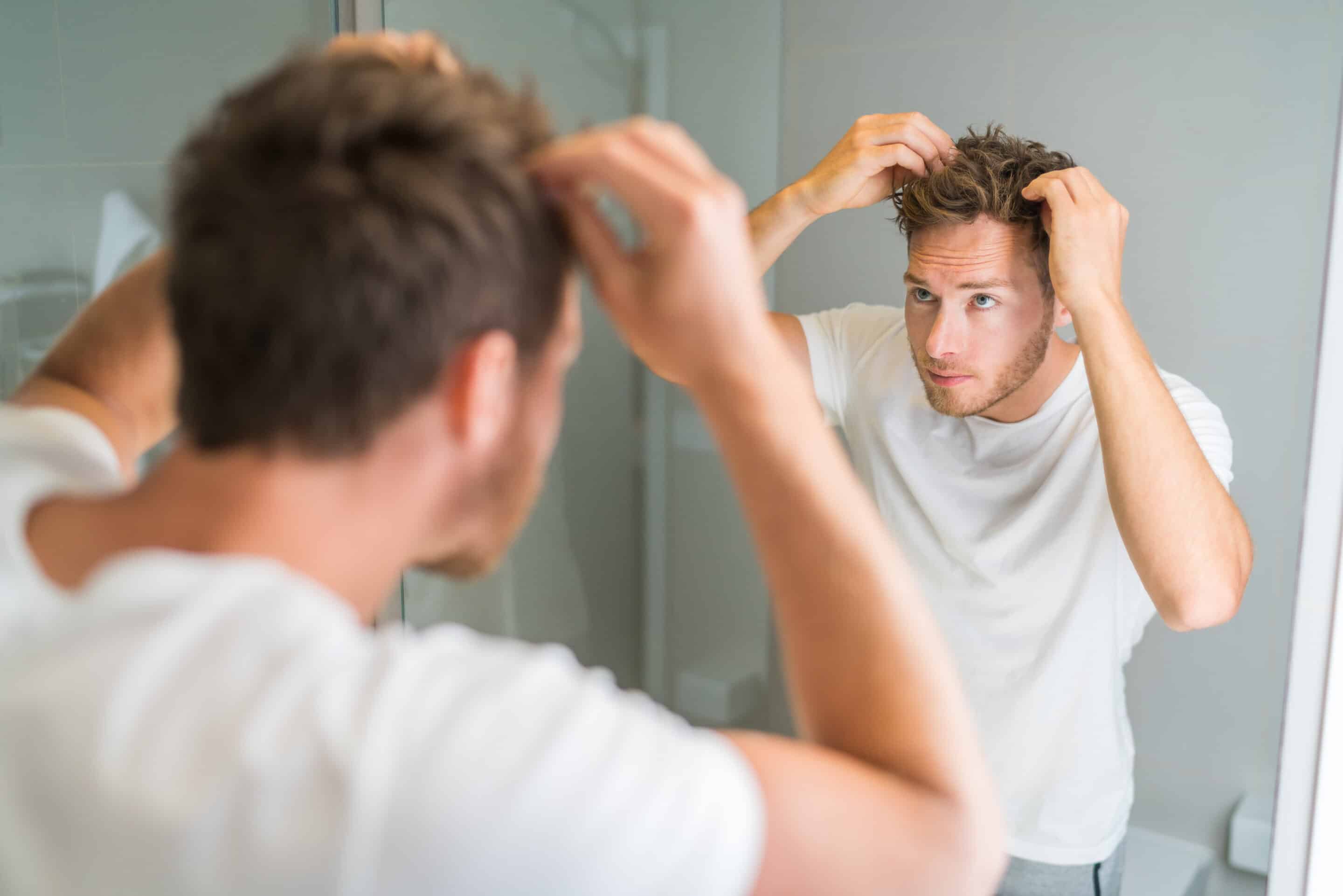 Man looking in the mirror, checking for male pattern baldness.